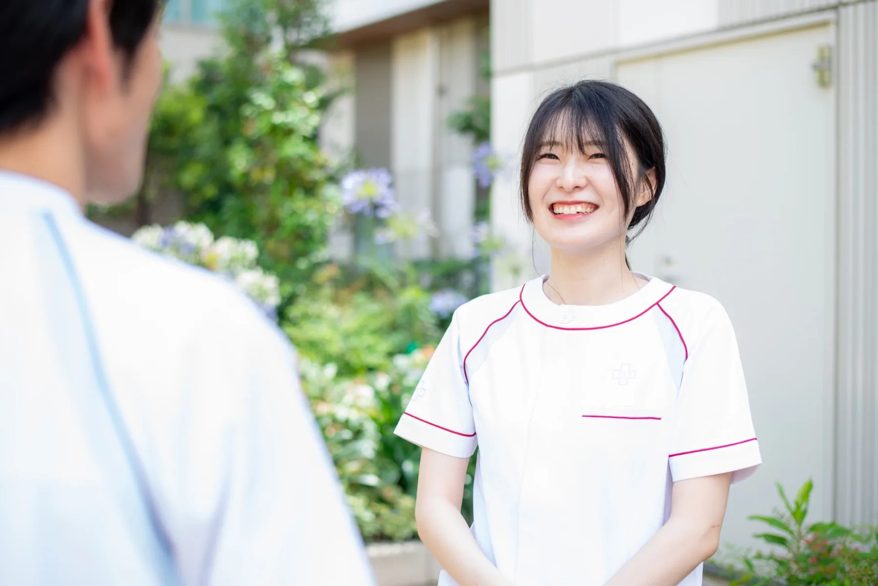 白金リハの白いユニフォームを着たスタッフが笑顔で話している写真